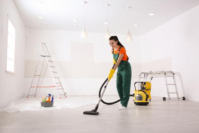 Photo of Professional janitor cleaning room with vacuum after renovation