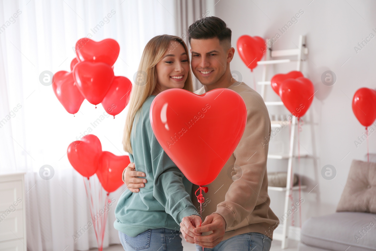 Photo of Lovely couple with heart shaped balloons indoors. Valentine's day celebration