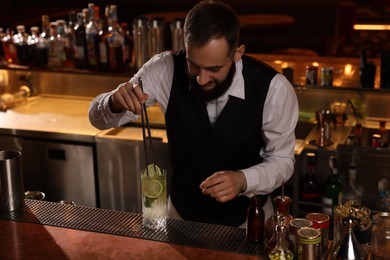 Photo of Bartender making fresh alcoholic cocktail at bar counter