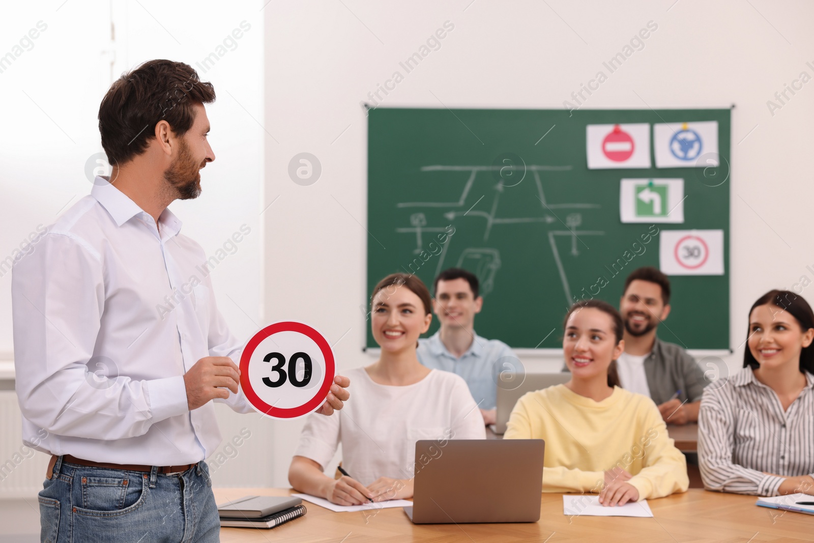 Photo of Teacher showing Speed Limit road sign during lesson in driving school