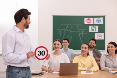 Photo of Teacher showing Speed Limit road sign during lesson in driving school