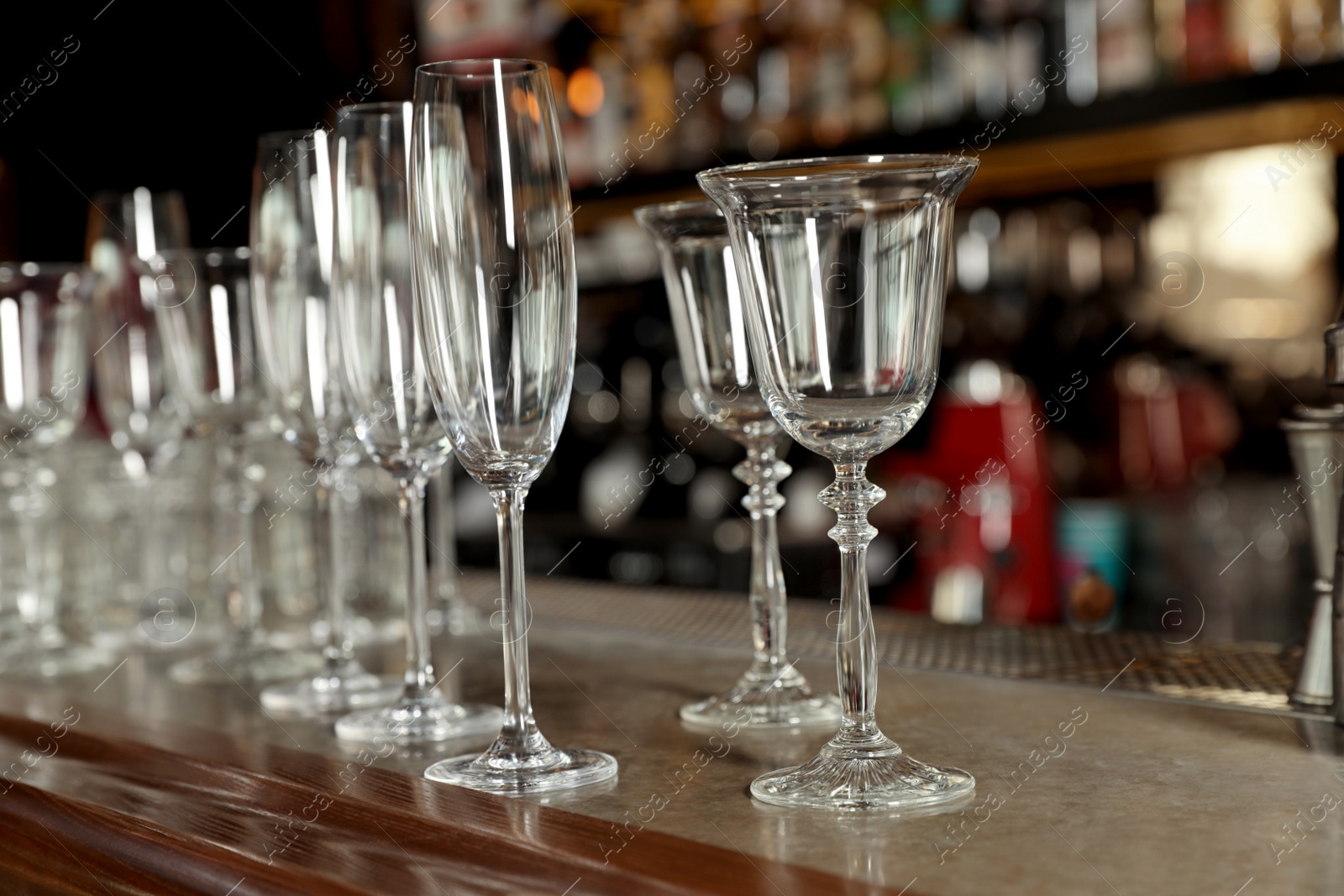 Photo of Different empty clean glasses on counter in bar