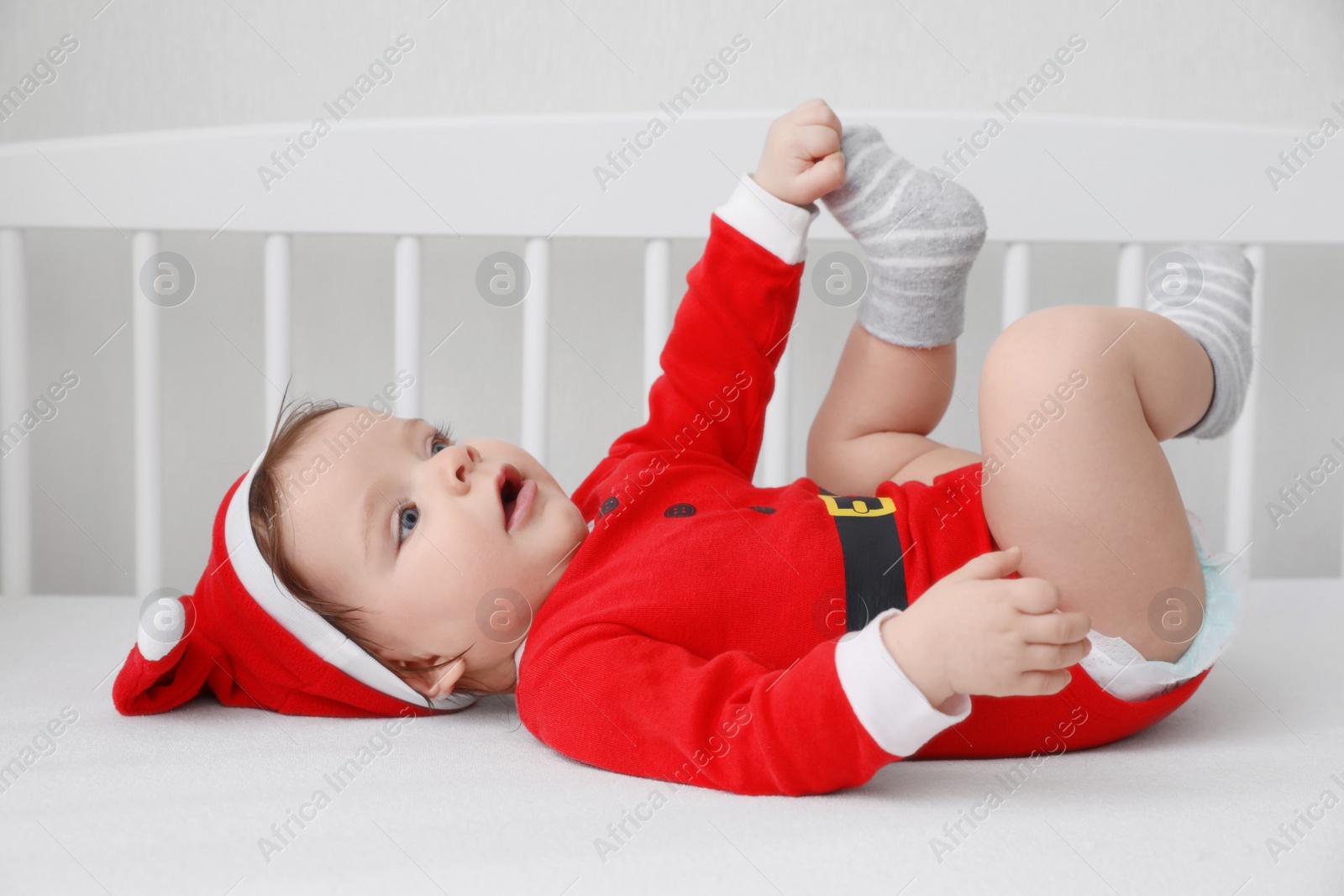 Photo of Cute baby wearing festive Christmas costume lying in crib