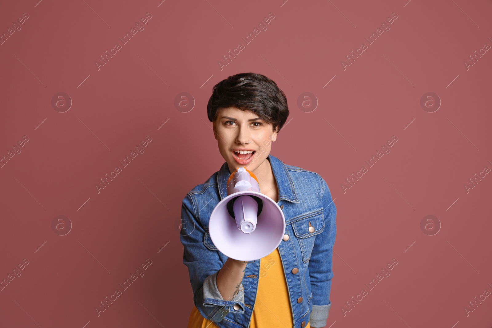 Photo of Young woman with megaphone on color background