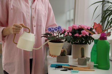 Photo of Woman watering beautiful house plant indoors, closeup