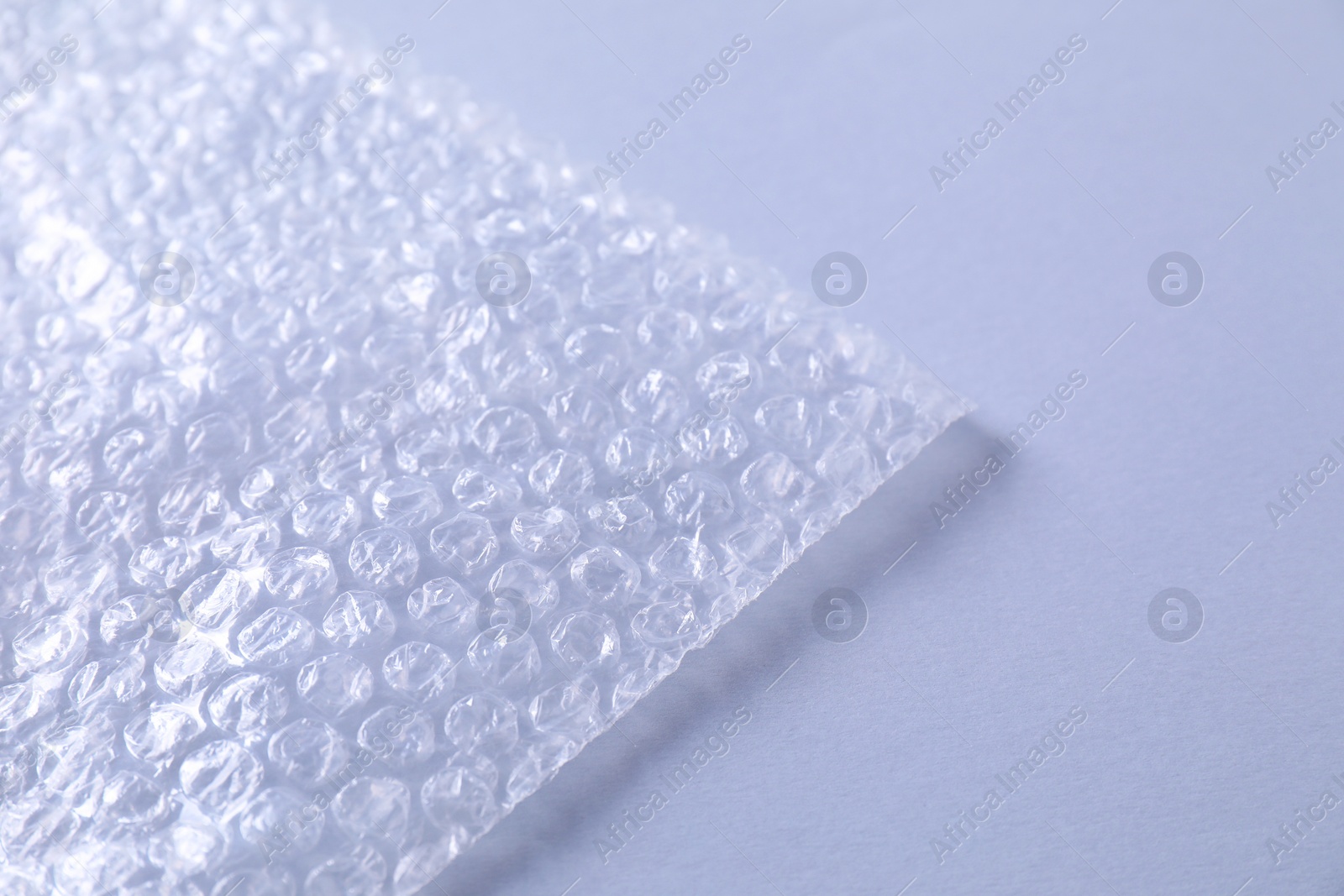 Photo of Transparent bubble wrap on gray background, closeup. Space for text