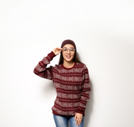 Young woman in warm sweater and hat on white background. Celebrating Christmas