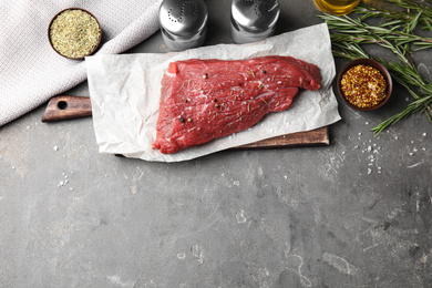 Photo of Flat lay composition with fresh beef cut on grey table. Space for text