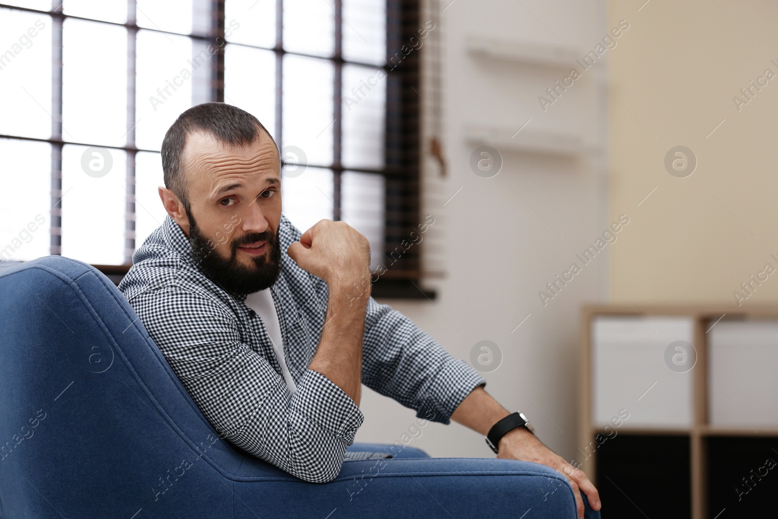 Photo of Portrait of handsome mature man sitting in armchair at home