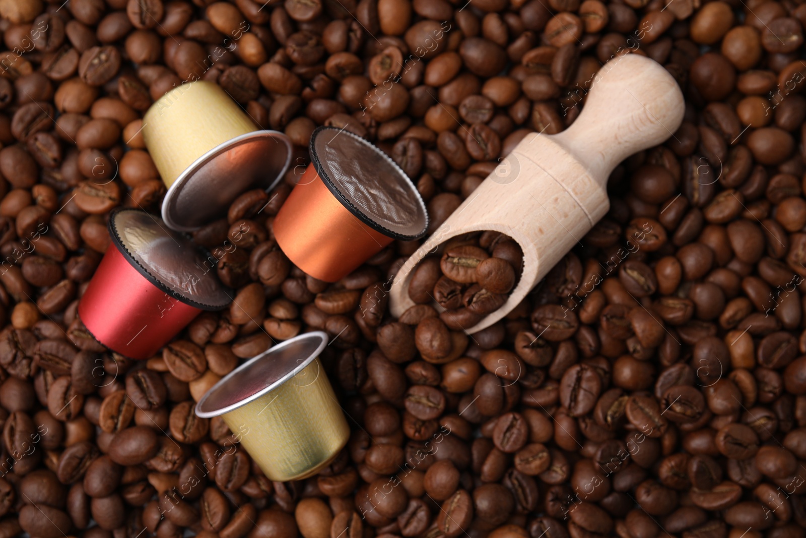 Photo of Many different coffee capsules and scoop on beans, top view