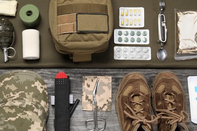 Photo of Flat lay composition with first aid kit and army boots on wooden table
