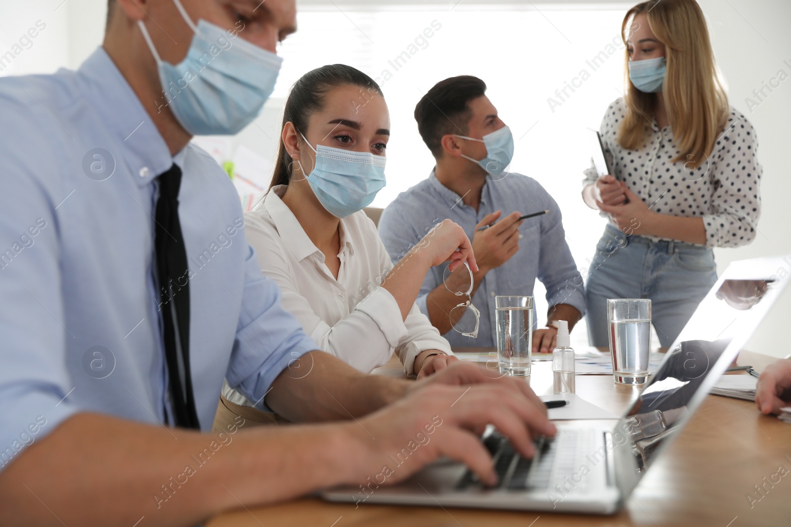 Photo of Group of coworkers with protective masks in office. Business meeting during COVID-19 pandemic