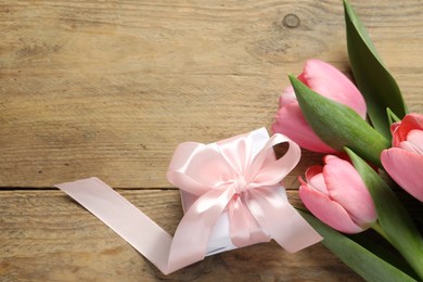 Happy Mother's Day. Beautiful pink tulips and gift box on wooden table, flat lay. Space for text