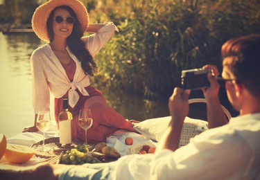 Man taking picture of girlfriend on pier at picnic