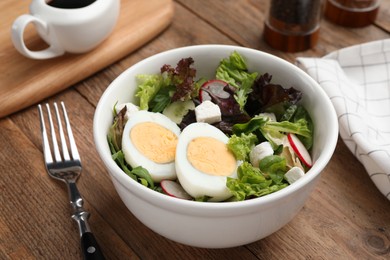 Photo of Delicious salad with boiled egg, feta cheese and vegetables on wooden table, closeup