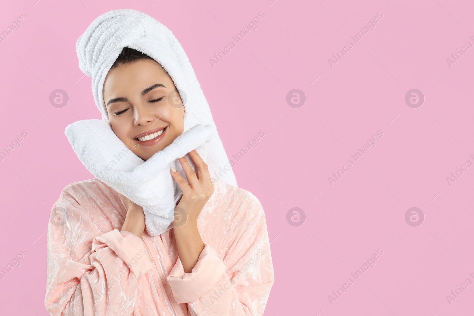 Photo of Young woman wiping face with towel on pink background. Space for text