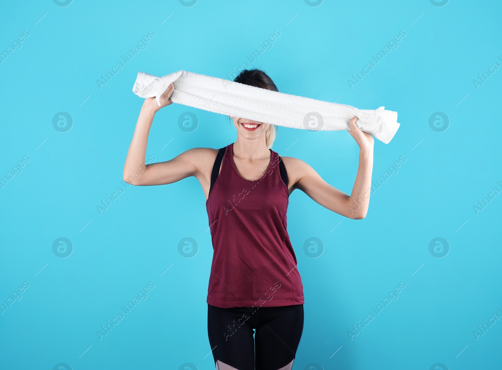 Photo of Beautiful young woman in sportswear with towel on color background