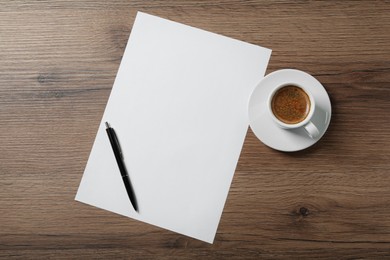 Photo of Blank paper sheet, pen and cup of coffee on wooden table, flat lay. Space for text