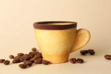 Delicious edible biscuit cup with espresso and coffee beans on beige background