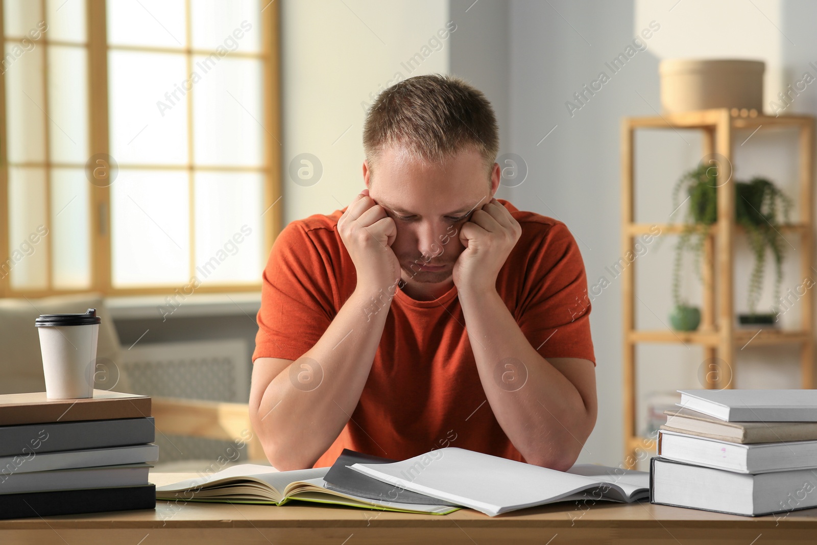 Photo of Tired man studying at wooden table indoors