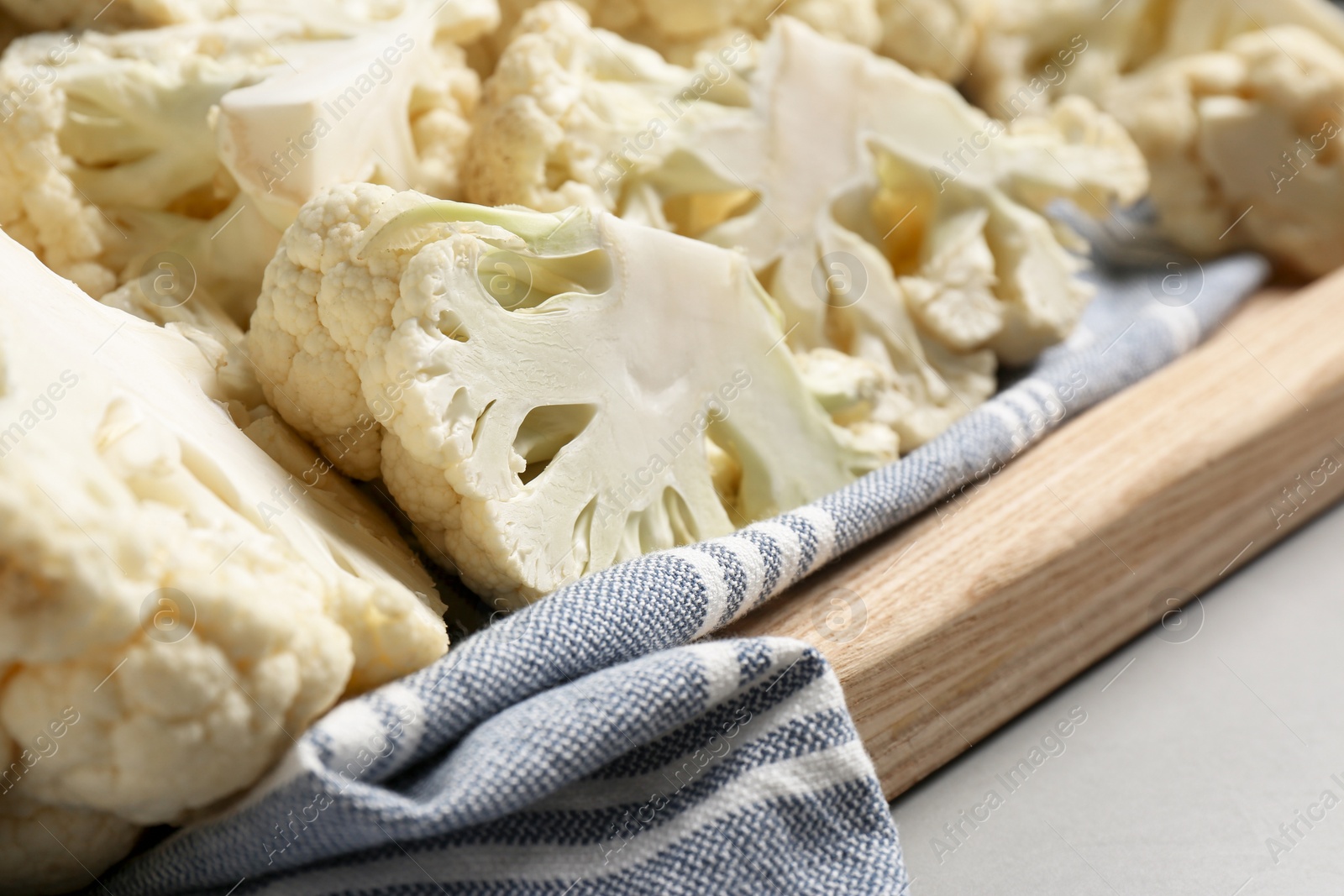 Photo of Cut fresh raw cauliflower on light grey table, closeup