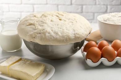 Photo of Fresh yeast dough, eggs and ingredients on white table. Making cake