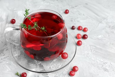 Photo of Delicious cranberry tea with thyme and berries on grey table, closeup