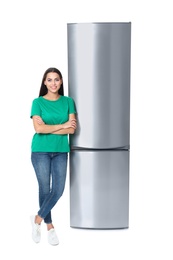 Young woman near closed refrigerator on white background