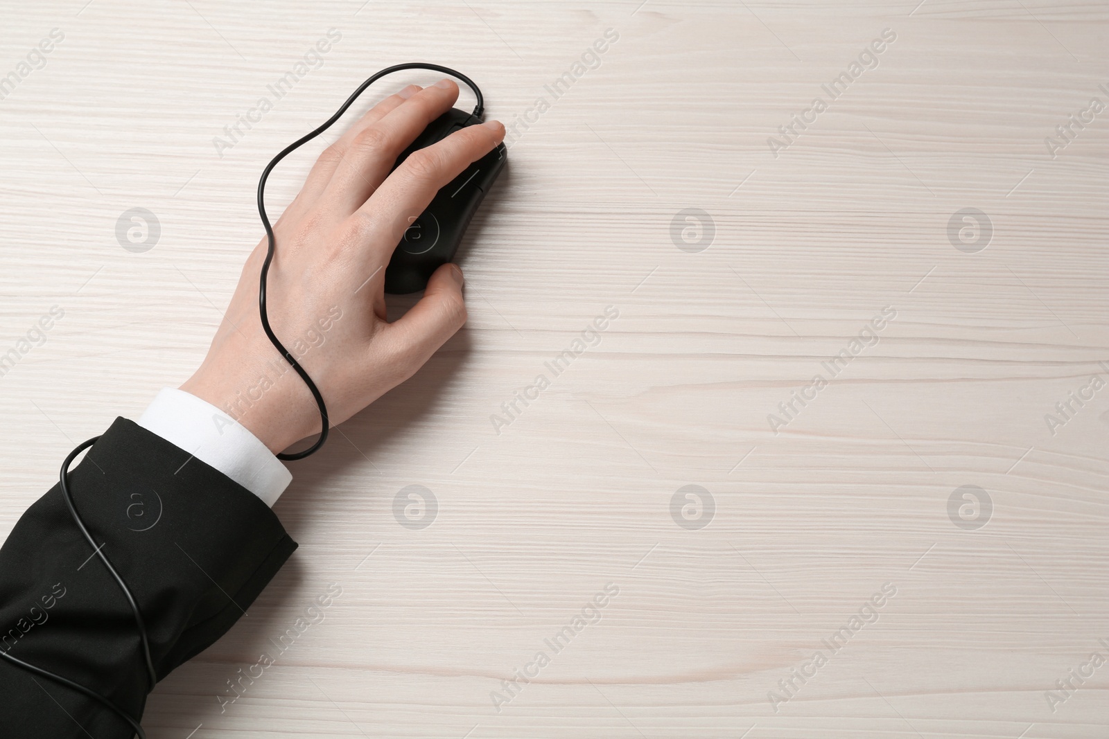 Photo of Internet addiction. Top view of man using computer mouse at wooden table, hand tied to device with cable