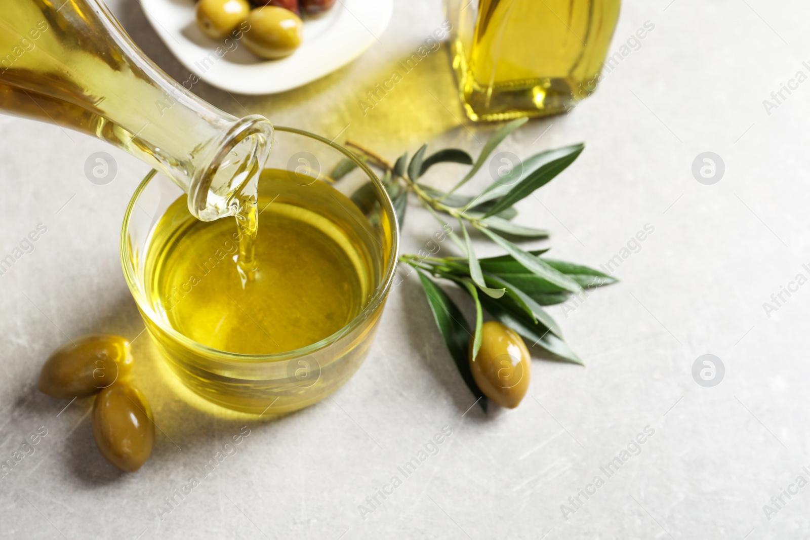 Photo of Pouring fresh olive oil into glass on table