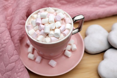 Photo of Cup of tasty cocoa with marshmallows, pink sweater and cookies on wooden table