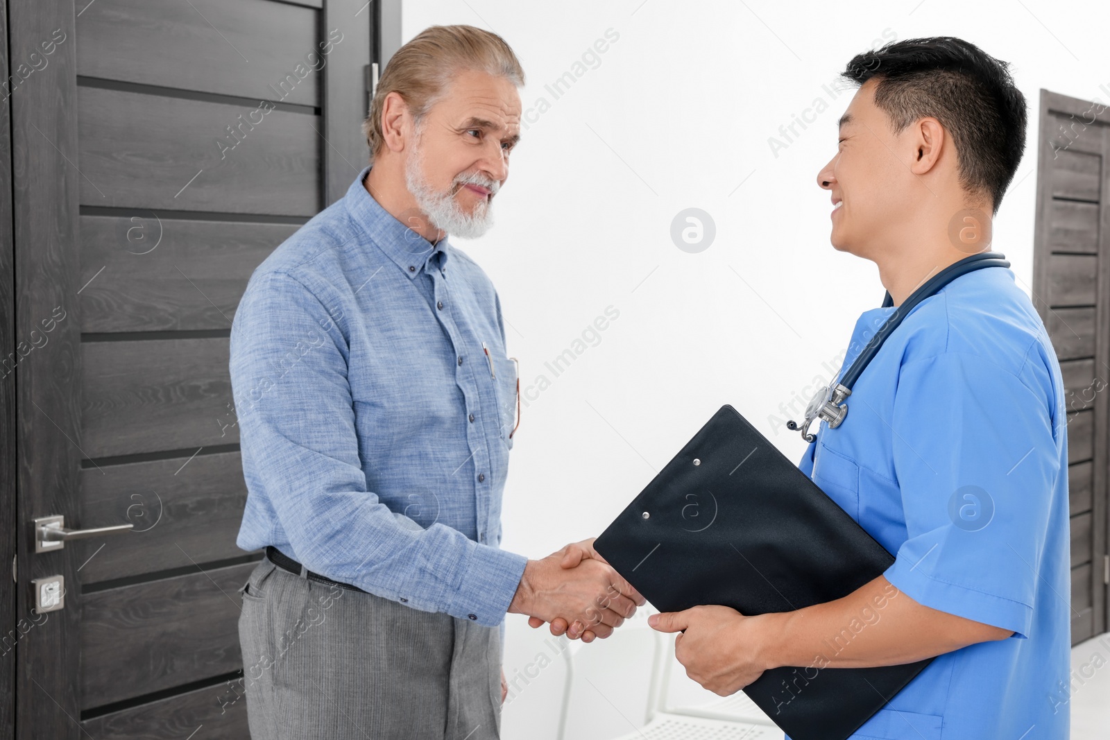 Photo of Happy doctor shaking hands with patient in hospital