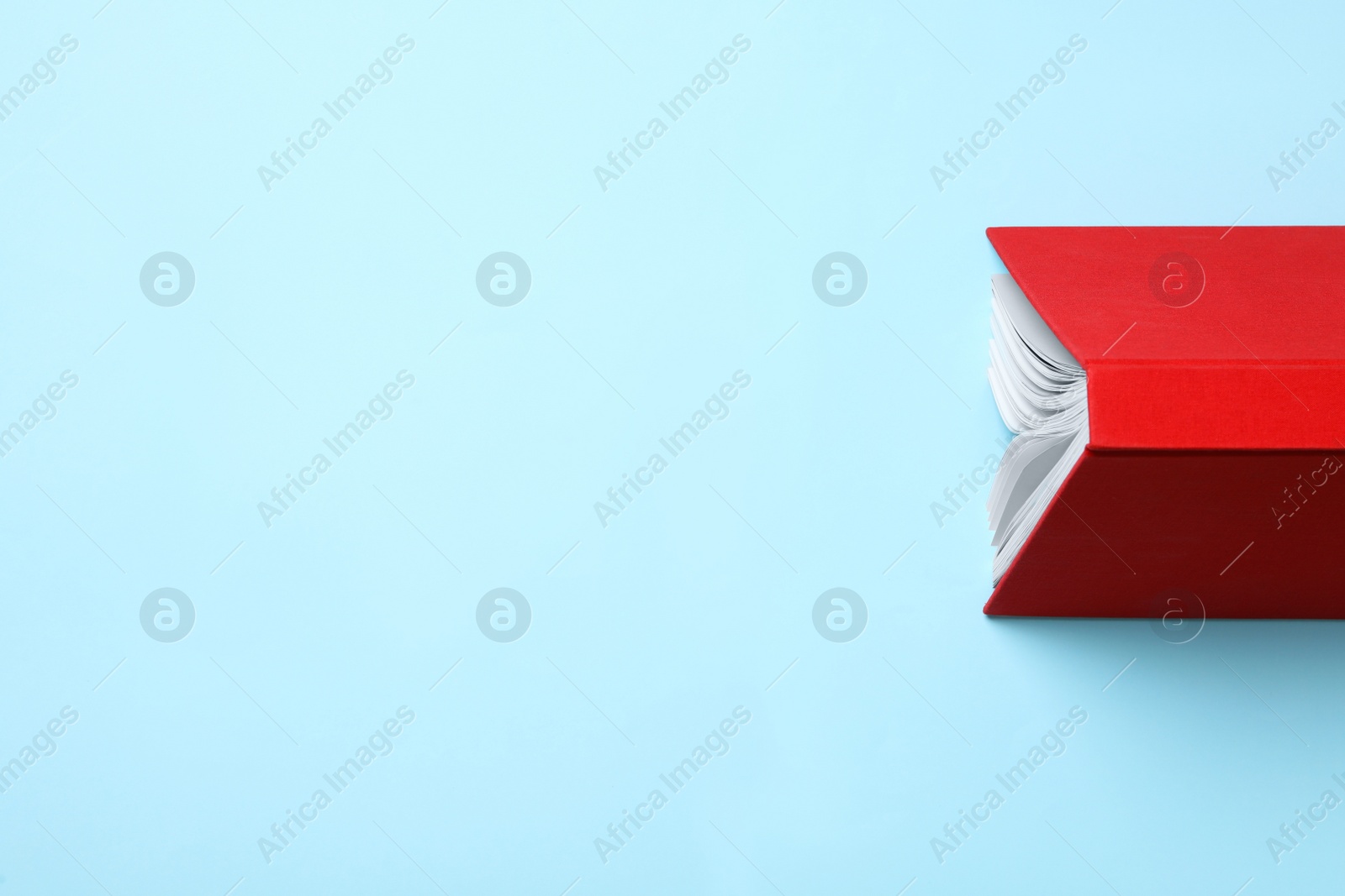 Photo of Book with red over on turquoise background, top view. Space for text