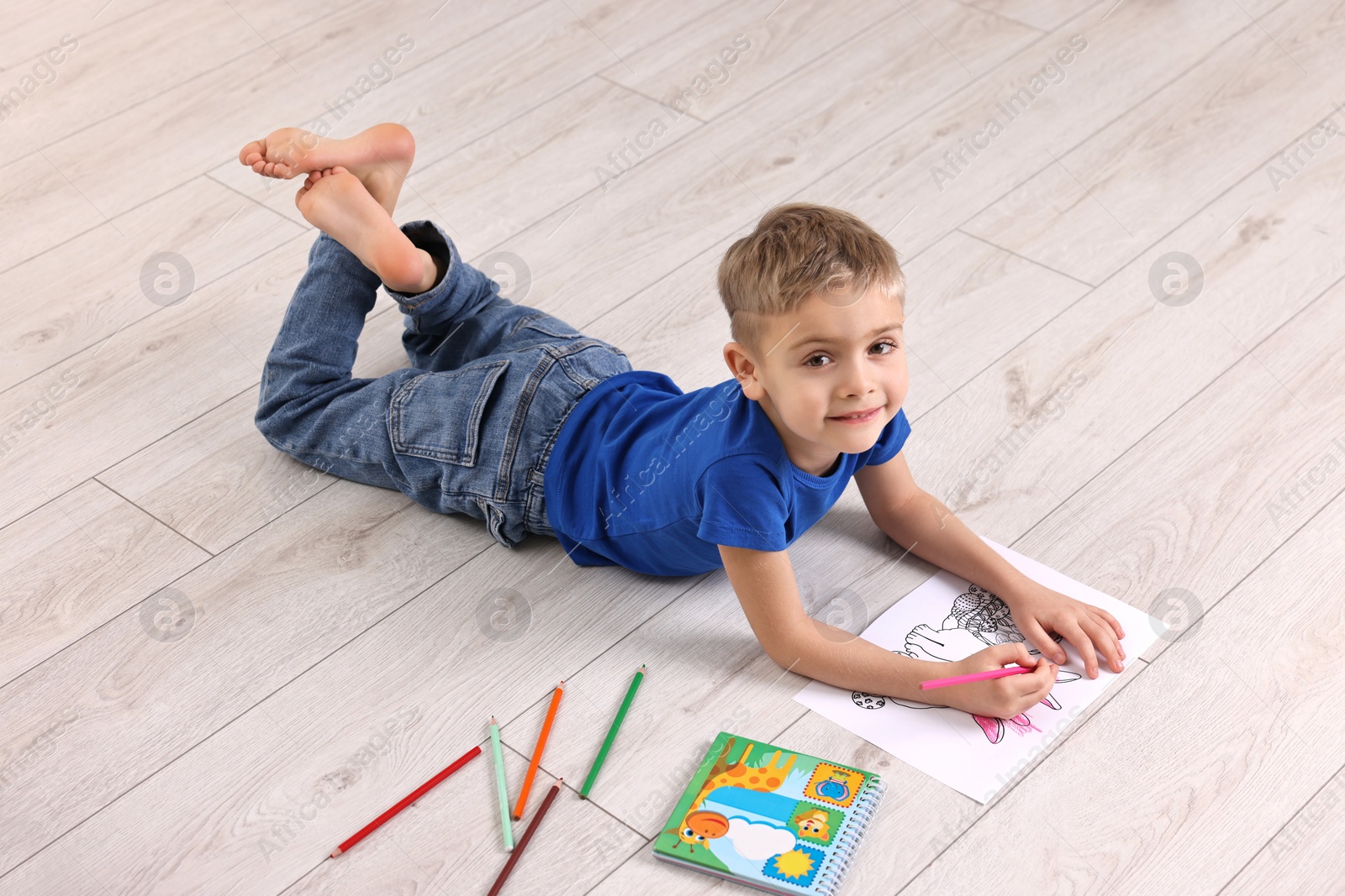 Photo of Cute little boy drawing on warm floor at home. Heating system