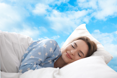 Image of Young woman sleeping in bed. Blue sky on background