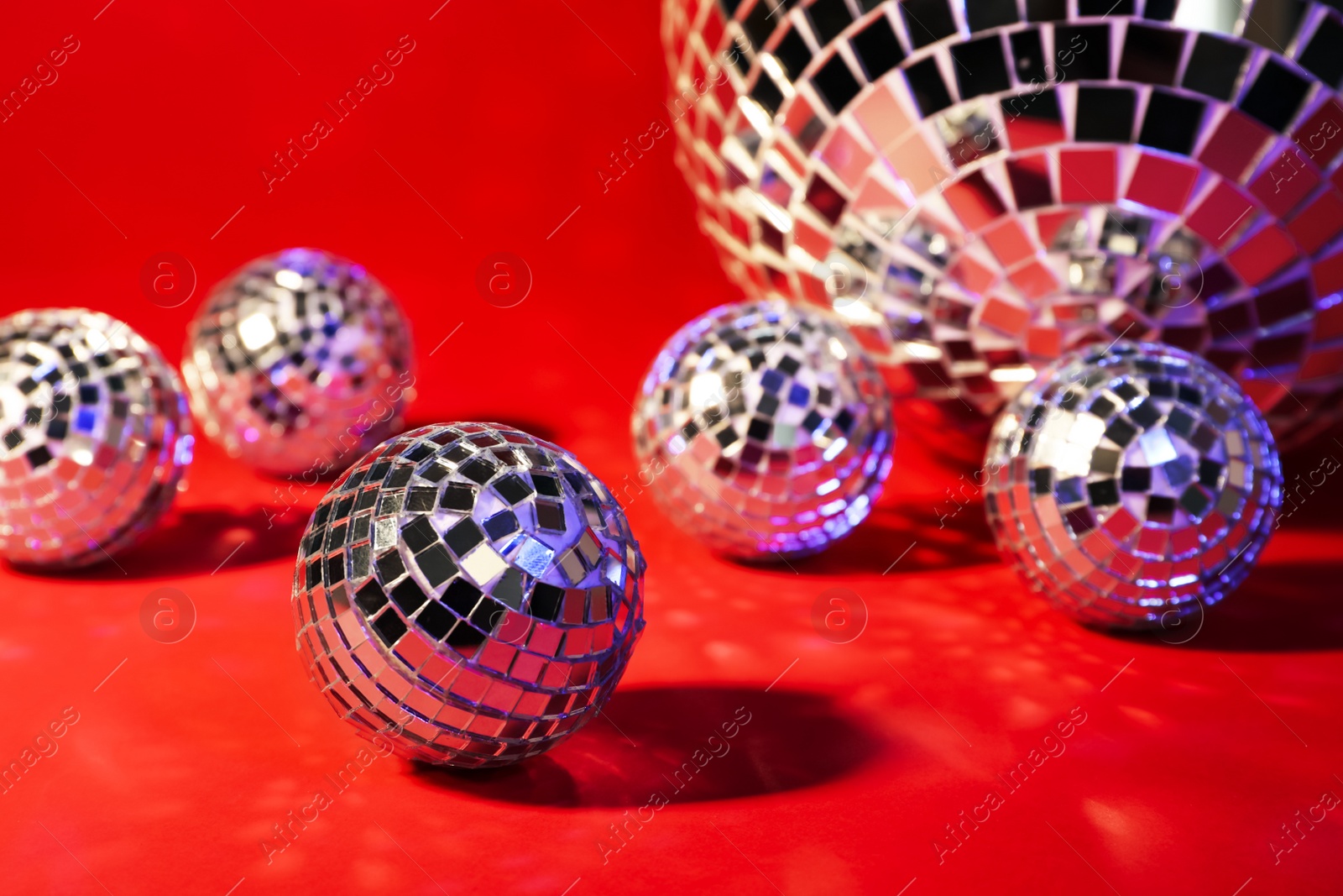 Photo of Beautiful shiny disco balls on red background, closeup