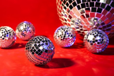 Beautiful shiny disco balls on red background, closeup