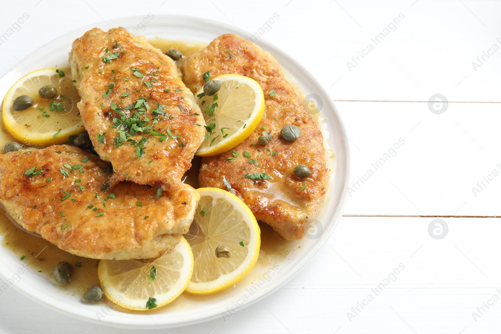 Photo of Delicious chicken piccata on white wooden table, closeup