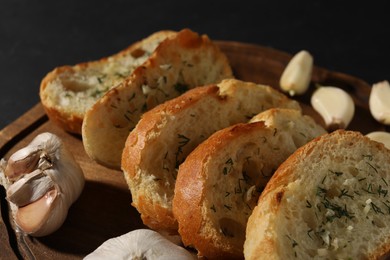 Photo of Tasty baguette with garlic and dill on wooden board, closeup