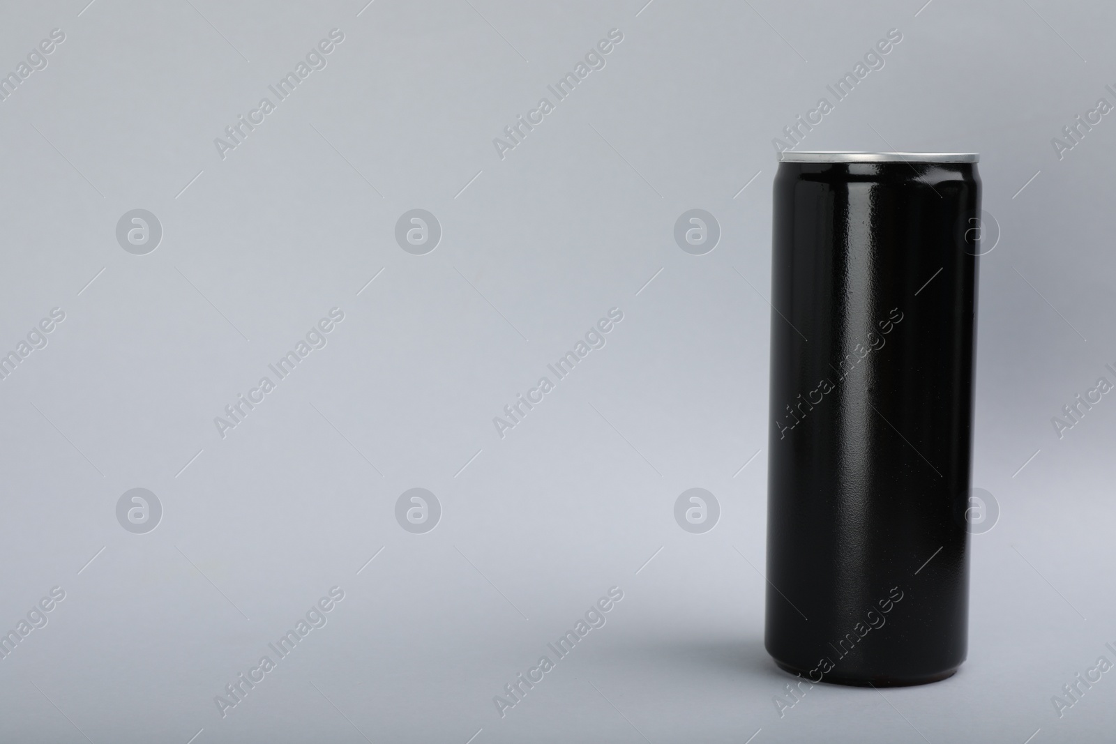 Photo of Black can of energy drink on light grey background. Space for text