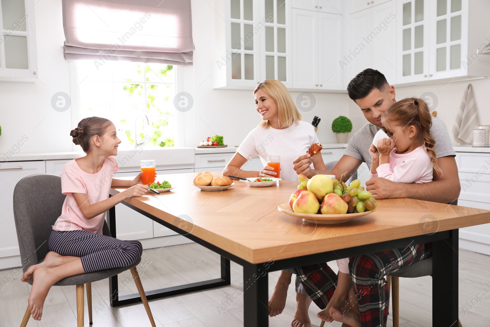 Photo of Happy family having breakfast together at table in modern kitchen