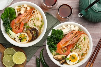 Photo of Delicious ramen with shrimps in bowls served on wooden table, flat lay. Noodle soup