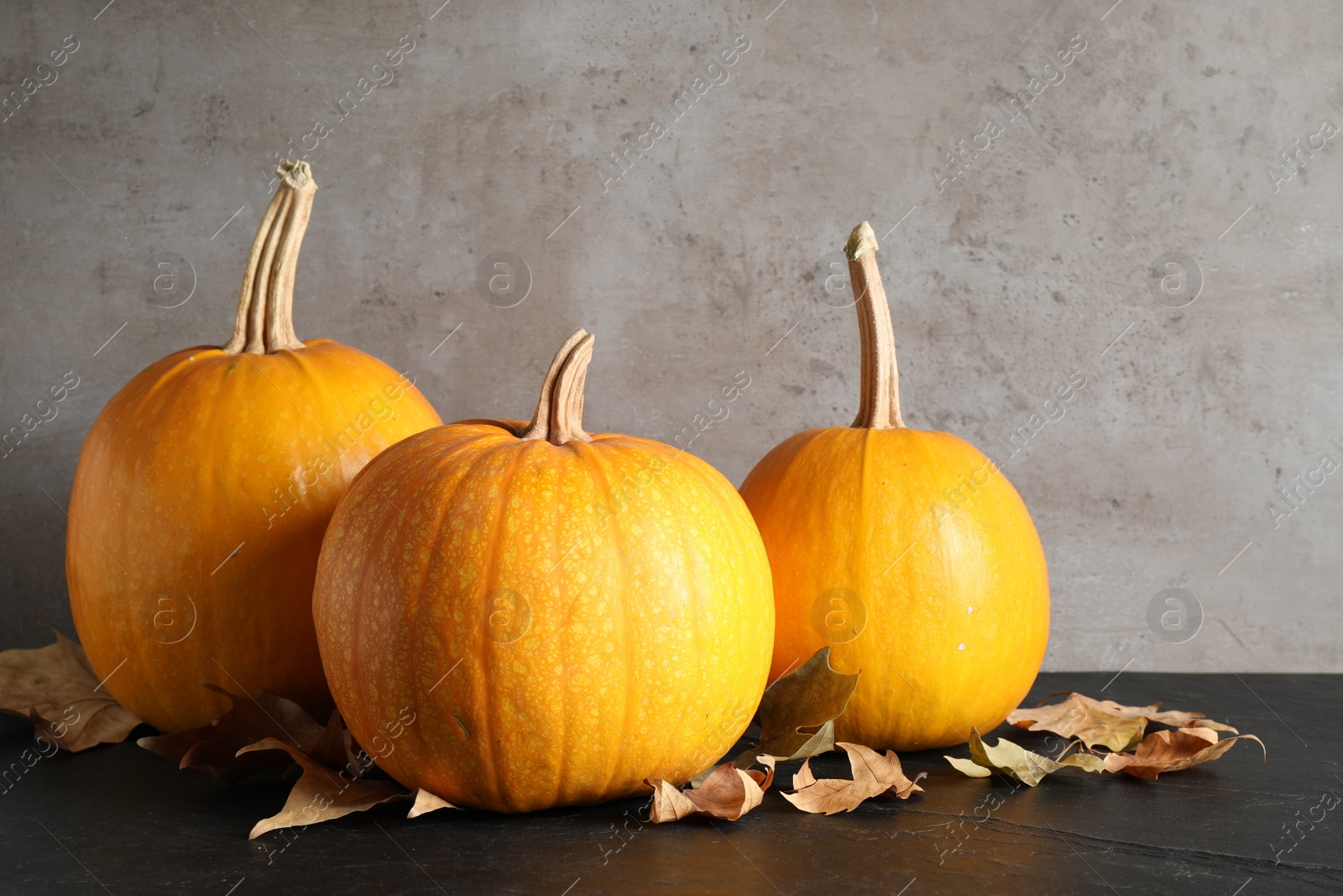 Photo of Ripe pumpkins and autumn leaves on black table