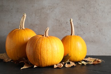 Photo of Ripe pumpkins and autumn leaves on black table