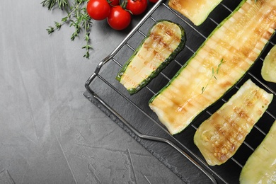 Flat lay composition with delicious grilled zucchini slices on grey table. Space for text