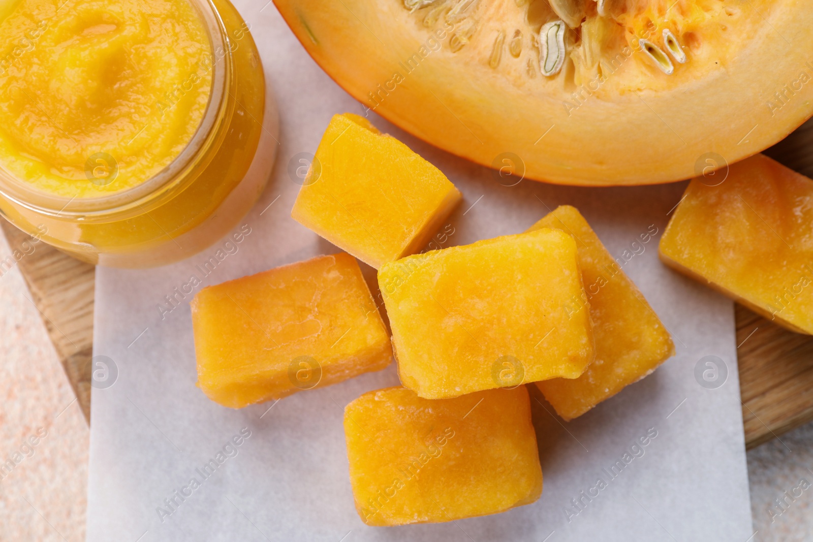 Photo of Frozen pumpkin puree cubes with ingredient on beige table, top view