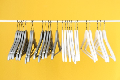 Photo of Metal rack with clothes hangers on color background