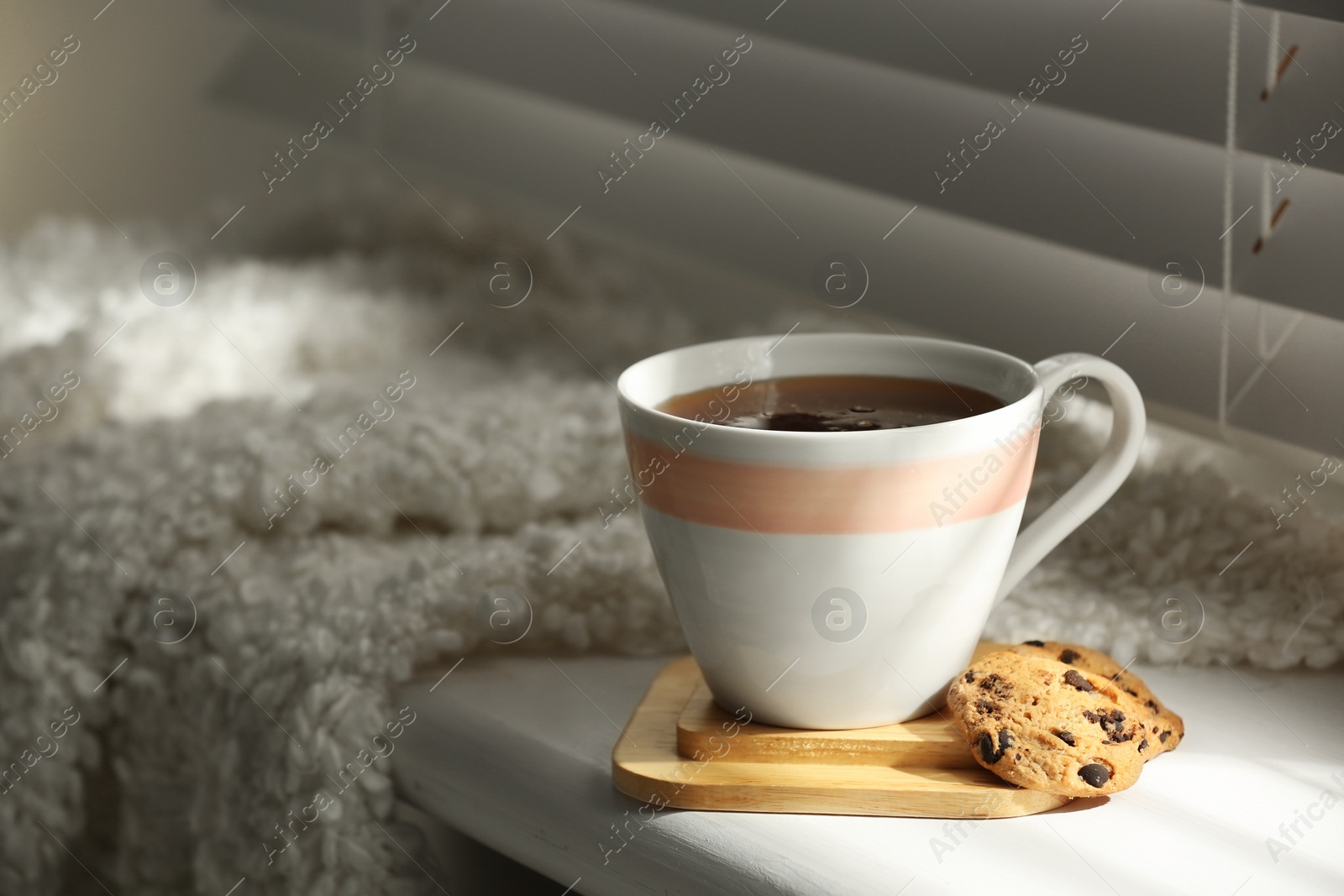 Photo of Cup of hot winter drink and cookies on windowsill indoors