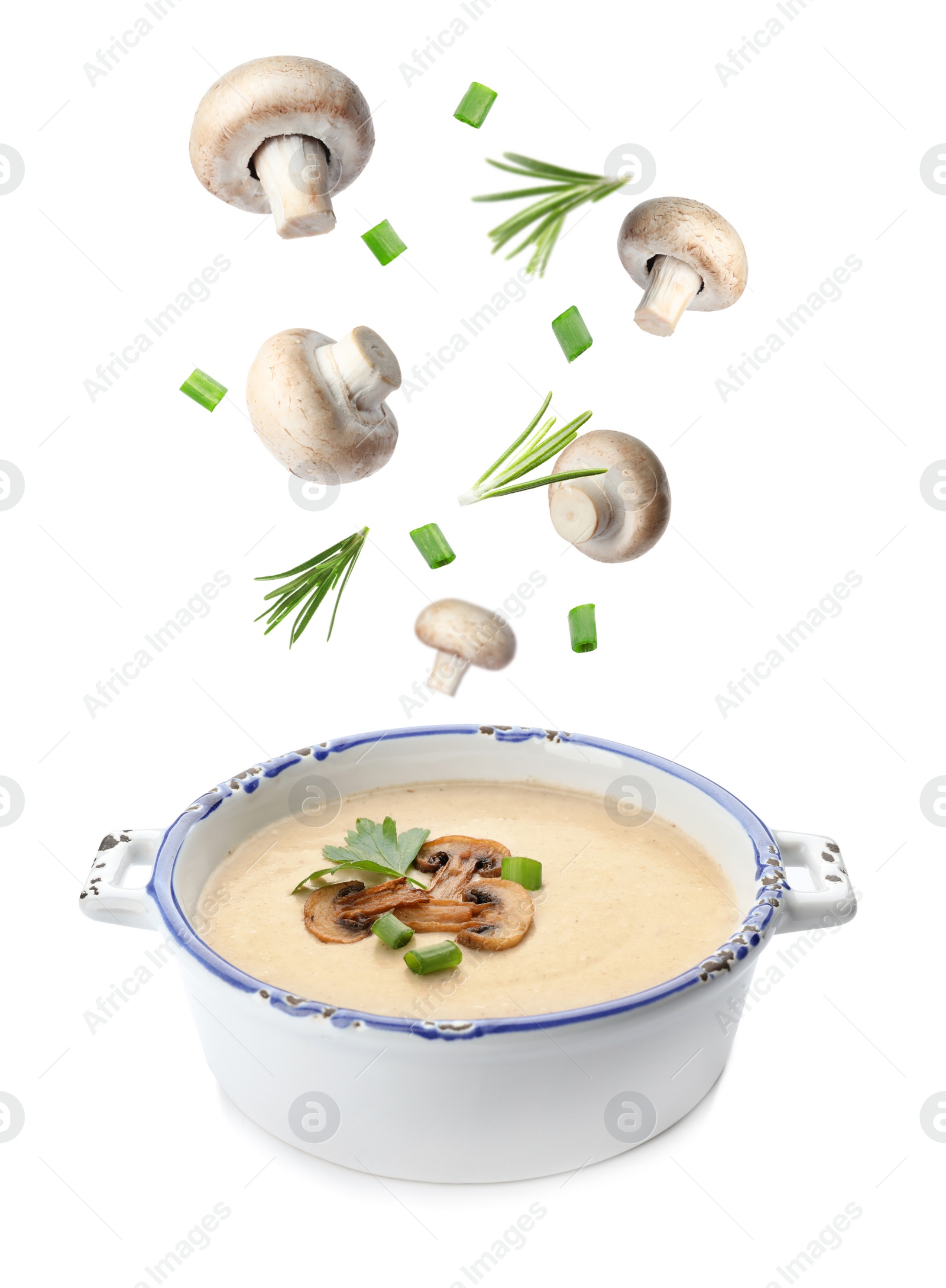 Image of Many different ingredients falling into bowl with homemade mushroom soup on white background