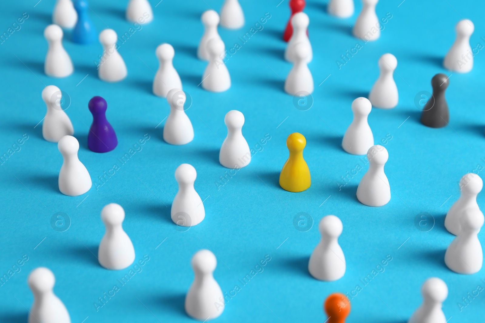 Photo of Colorful pawns on light blue background. Social inclusion concept